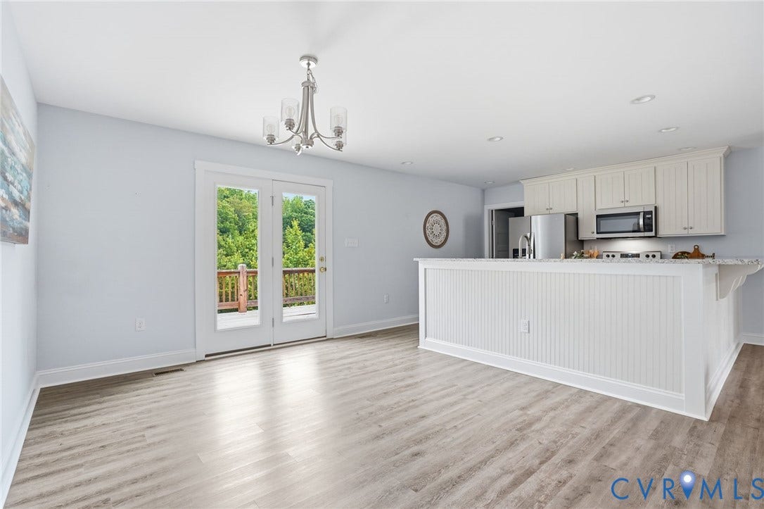 2677 Dogtown Road, Goochland, VA 23063 Open-concept living area featuring light wood-finish flooring, white trim, and a white beadboard kitchen island