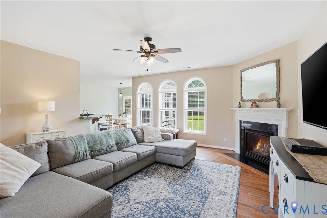 5305 Wellington Ridge Road, Richmond, VA 23231 Living area featuring wood-finish flooring, a fireplace with a white mantel, and three arched windows
