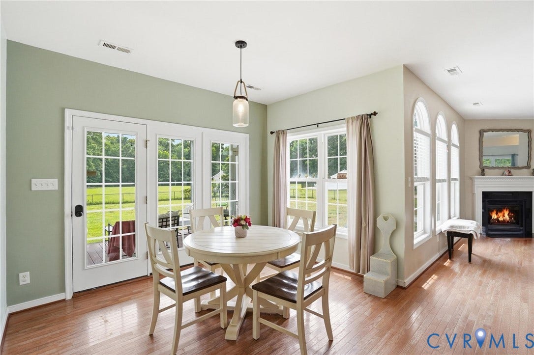 5305 Wellington Ridge Road, Richmond, VA 23231 Open-concept living space featuring wood-finish flooring, a white mantel fireplace, and a wall of three arched windows with blinds