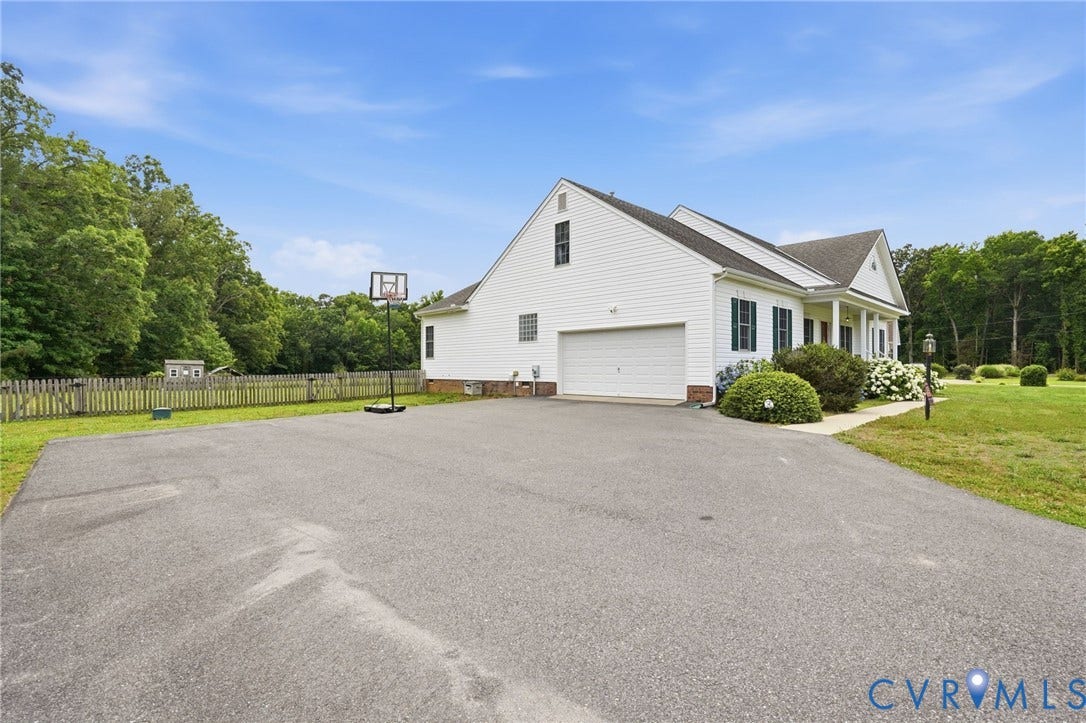 5305 Wellington Ridge Road, Richmond, VA 23231 Expansive asphalt driveway leading to a white siding residence with an attached two-car garage