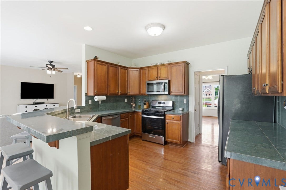 5305 Wellington Ridge Road, Richmond, VA 23231 Kitchen featuring wood-finish cabinetry, stainless steel appliances, tile countertops, and a tile backsplash