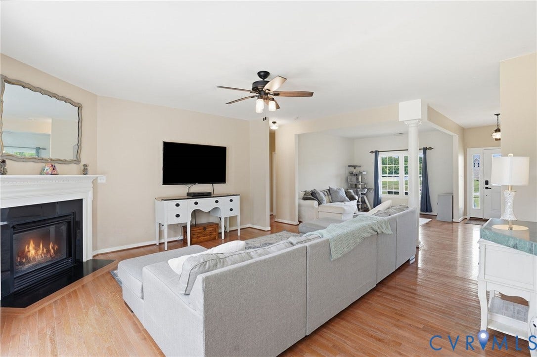 5305 Wellington Ridge Road, Richmond, VA 23231 Living area featuring wood-finish flooring, a white mantel fireplace with a black surround, and a ceiling fan with integrated lighting