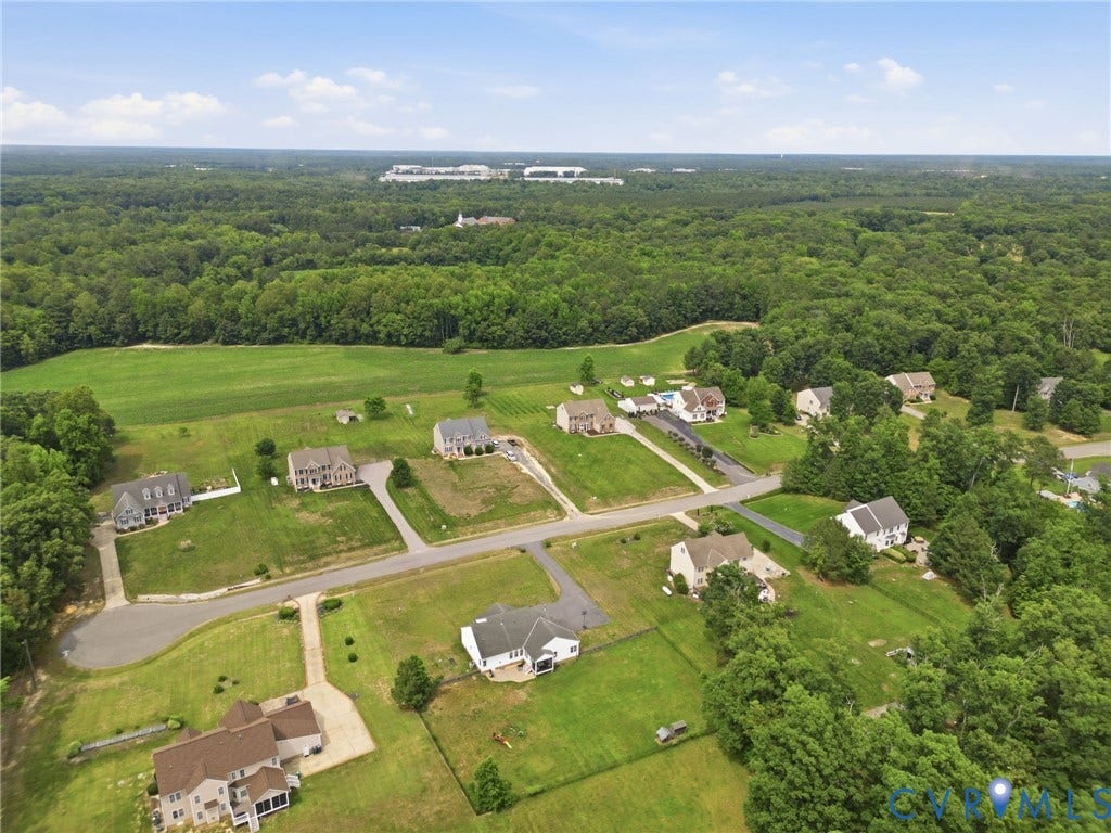5305 Wellington Ridge Road, Richmond, VA 23231 Aerial perspective showcasing a residential community with paved roads, individual properties featuring manicured lawns, and surrounding mature trees