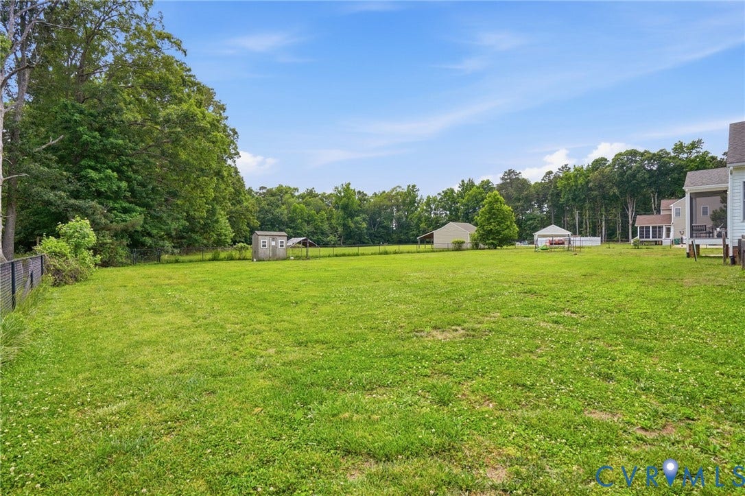 5305 Wellington Ridge Road, Richmond, VA 23231 Expansive green lawn with a black chain-link fence and mature perimeter trees