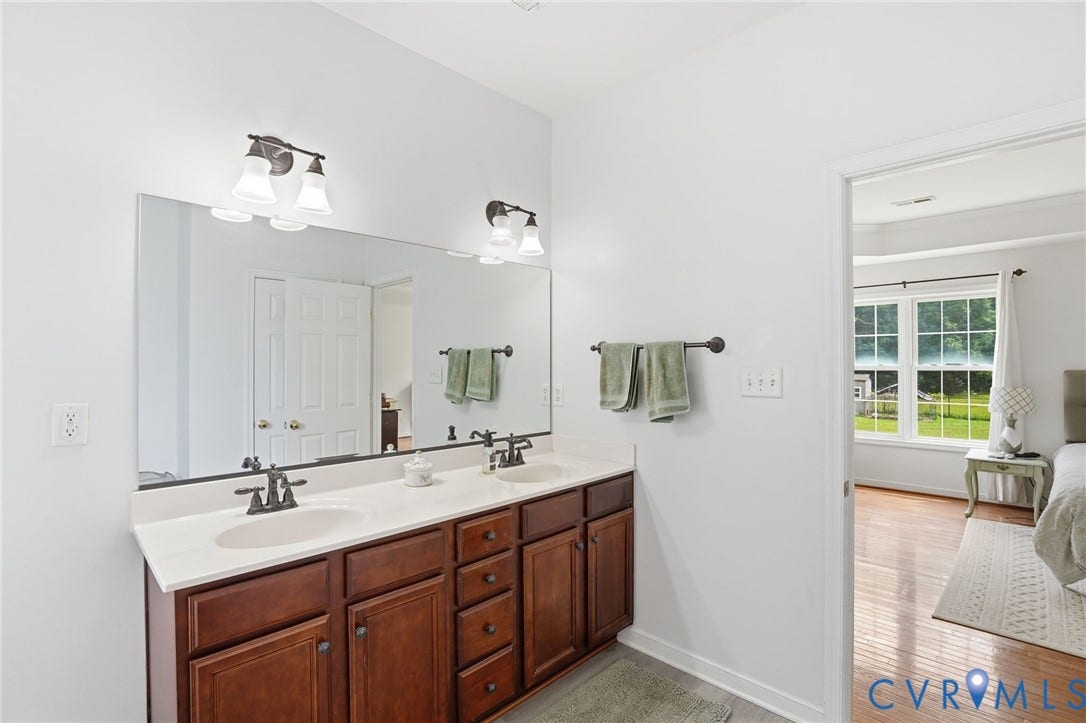 5305 Wellington Ridge Road, Richmond, VA 23231 Double vanity with dark wood cabinetry, white countertop, dual undermount sinks, and oil-rubbed bronze fixtures