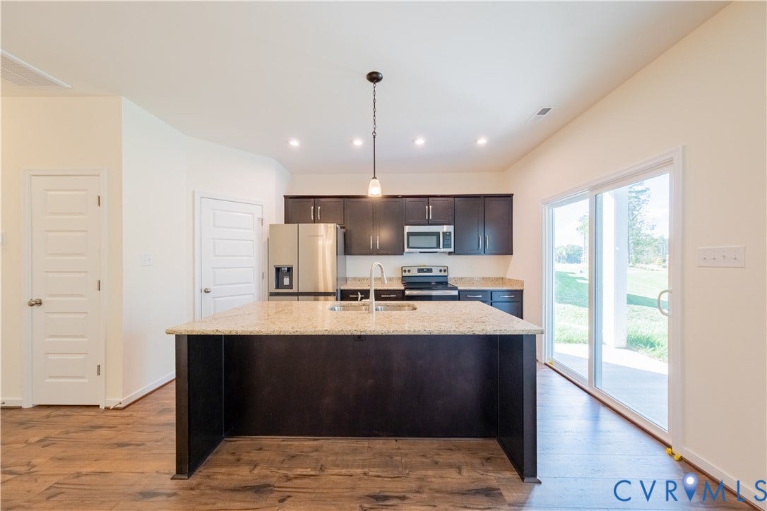 18372 Palisades Court, Chesterfield, VA 23120 Kitchen featuring an island with a light-toned countertop, dark wood-finish cabinetry, stainless steel appliances, and wood-finish flooring