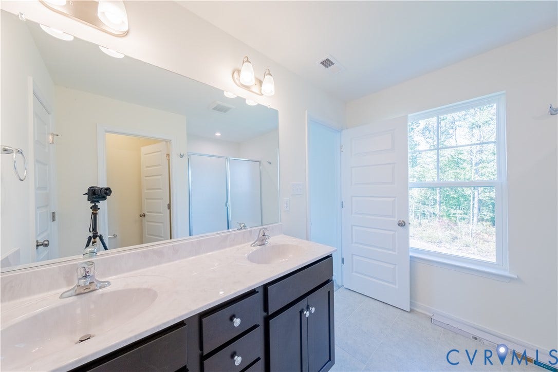 18372 Palisades Court, Chesterfield, VA 23120 Bathroom featuring a dual vanity with undermount sinks, a wide mirror, a three-light fixture, and a window