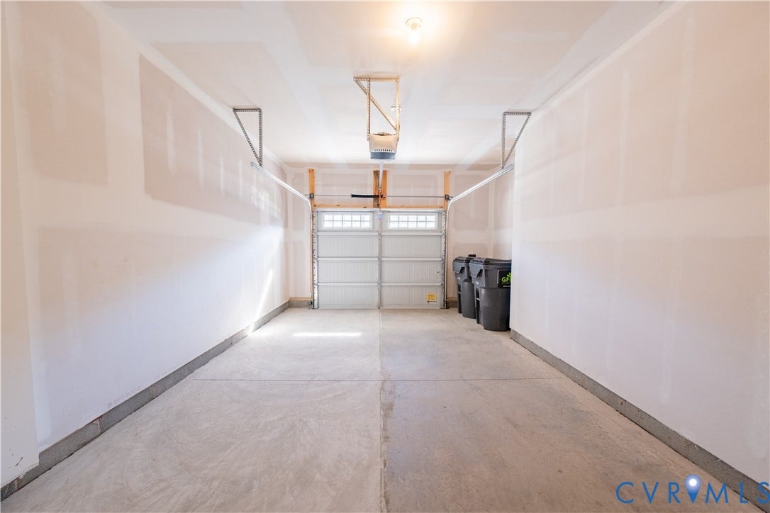18372 Palisades Court, Chesterfield, VA 23120 Spacious garage featuring a concrete floor, overhead lighting, garage door opener mechanism, and a panel-style garage door with upper window inserts