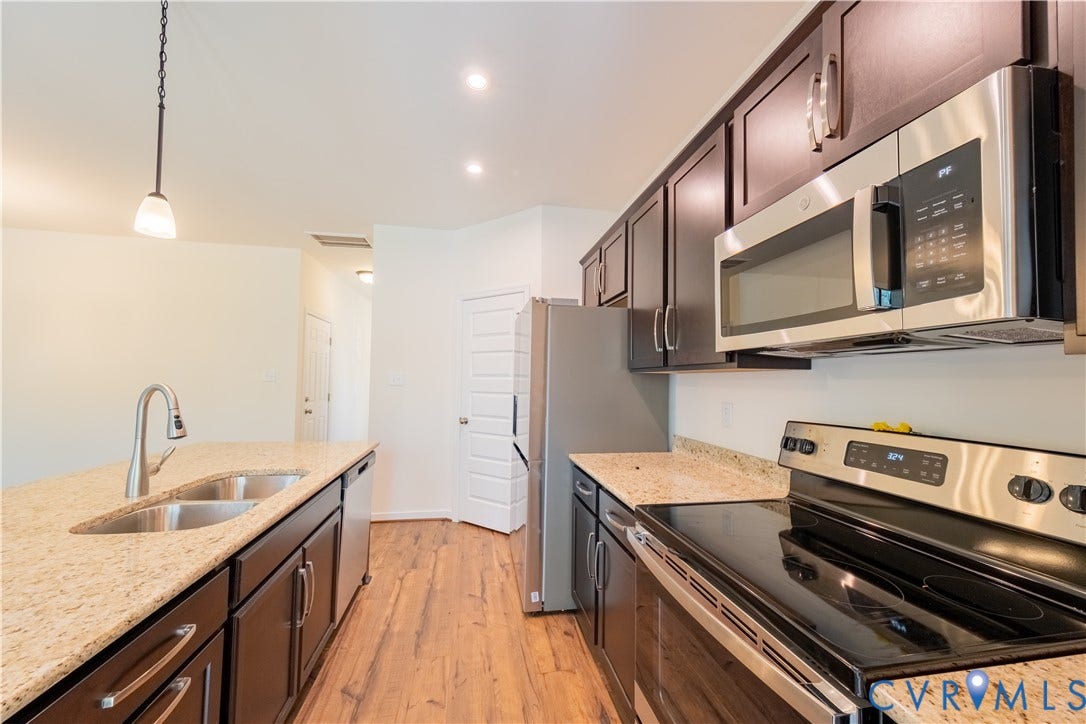 18372 Palisades Court, Chesterfield, VA 23120 Kitchen featuring wood-finish flooring, dark wood cabinetry, granite-finish countertops, stainless steel appliances, and an island with a double basin sink