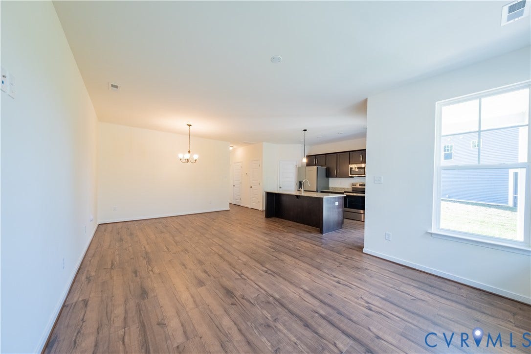 18372 Palisades Court, Chesterfield, VA 23120 Open-concept living space featuring wood-finish flooring, a kitchen island with pendant lighting, stainless steel appliances, and a window providing natural light