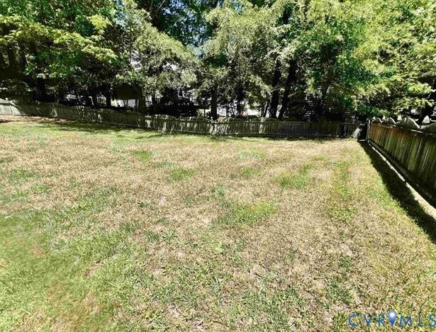 Expansive backyard featuring a partially treed perimeter and a wooden privacy fence