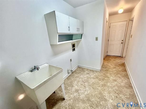 Utility room featuring a white laundry sink, white upper cabinetry, and patterned vinyl flooring