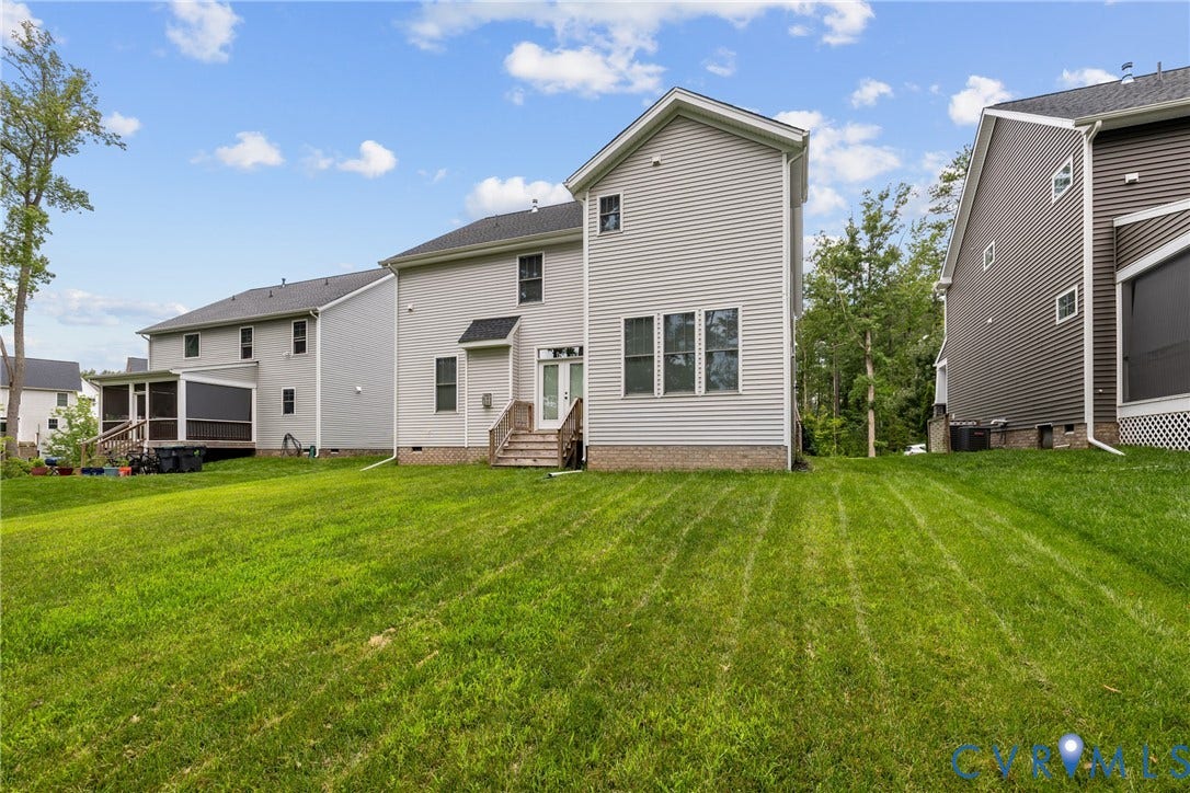 7125 Jones Run Lane, Glen Abby, Moseley, VA 23120 Green lawn with a light gray siding exterior, multiple windows, and a glass-paneled back door with wooden steps