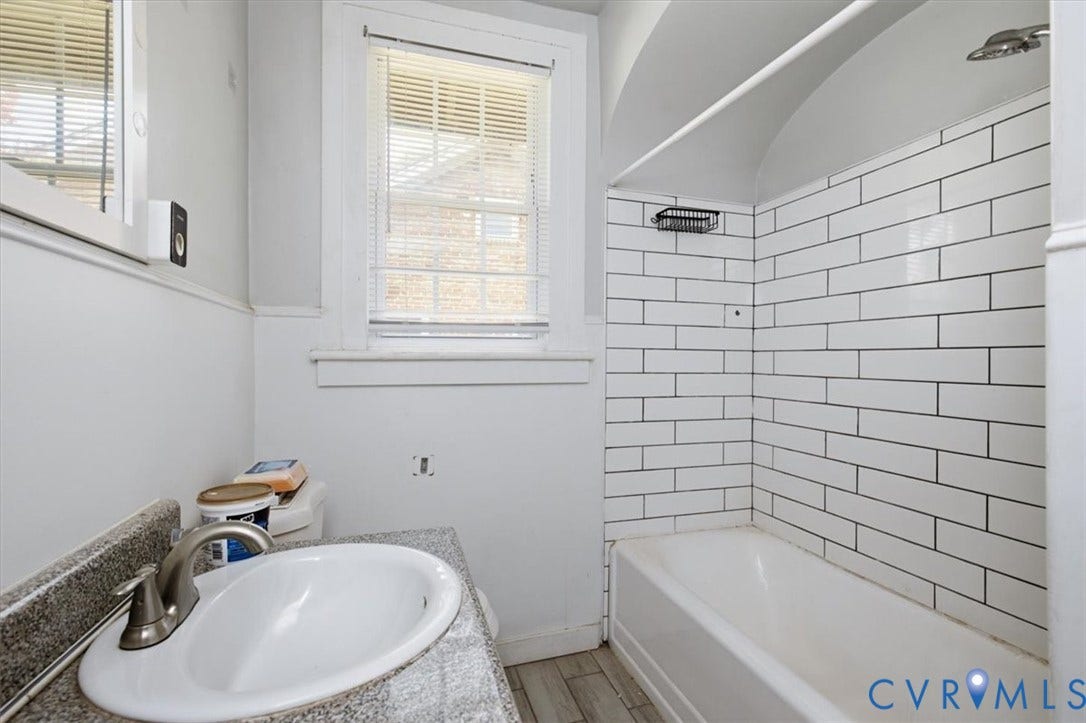 125 Richmond Avenue, Colonial Heights, VA 23834 Bathroom featuring a white subway tile shower surround, shower/tub combination, single vanity with a white basin sink, and wood-finish flooring
