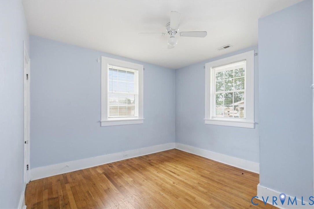 125 Richmond Avenue, Colonial Heights, VA 23834 Room featuring wood flooring, two windows with white trim, a white ceiling fan, and light blue walls