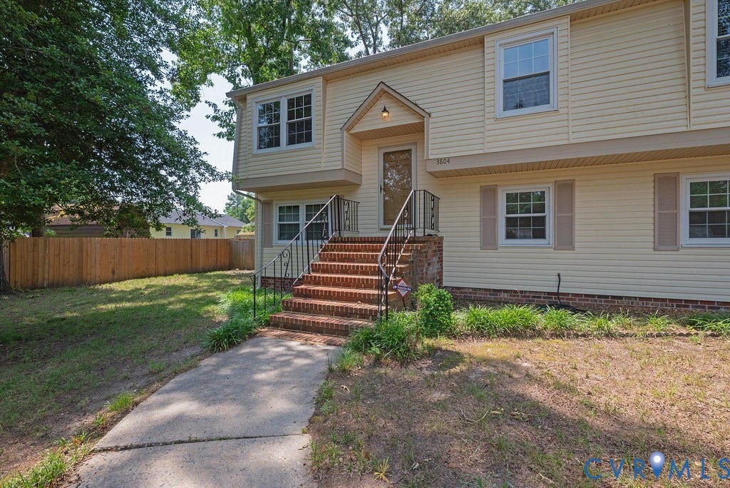 Two-story exterior with light yellow siding and a brick foundation