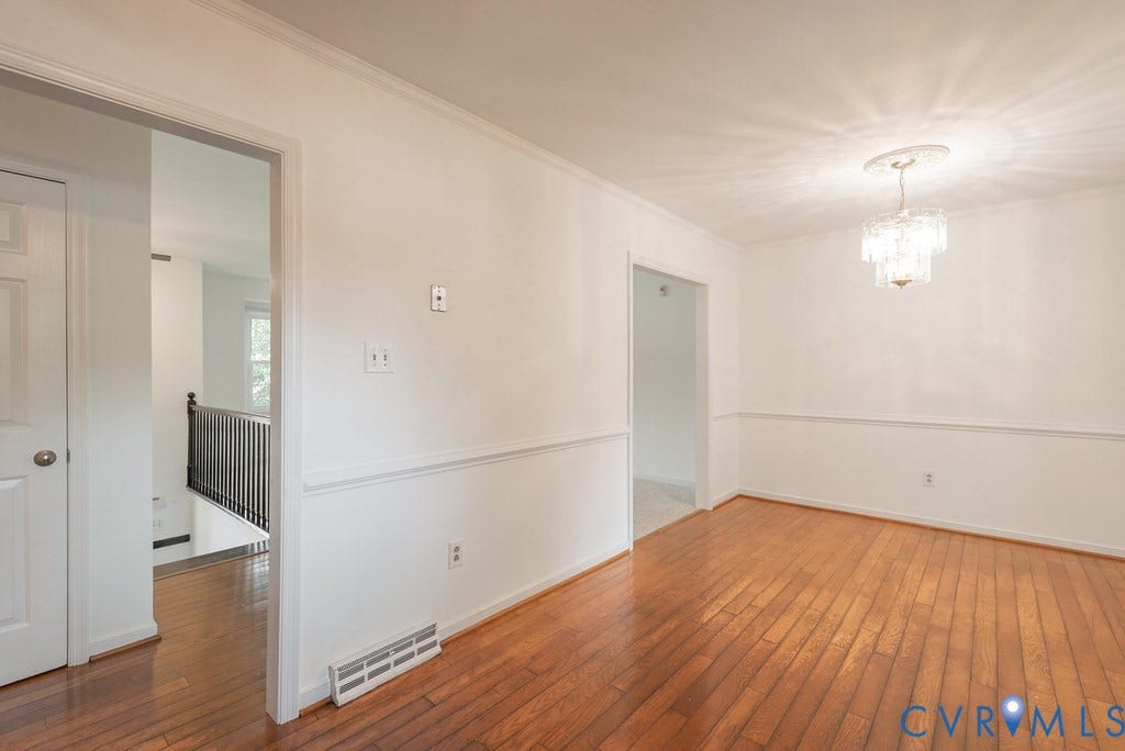 Bright interior space featuring wood-finish flooring, white walls, and a decorative chandelier