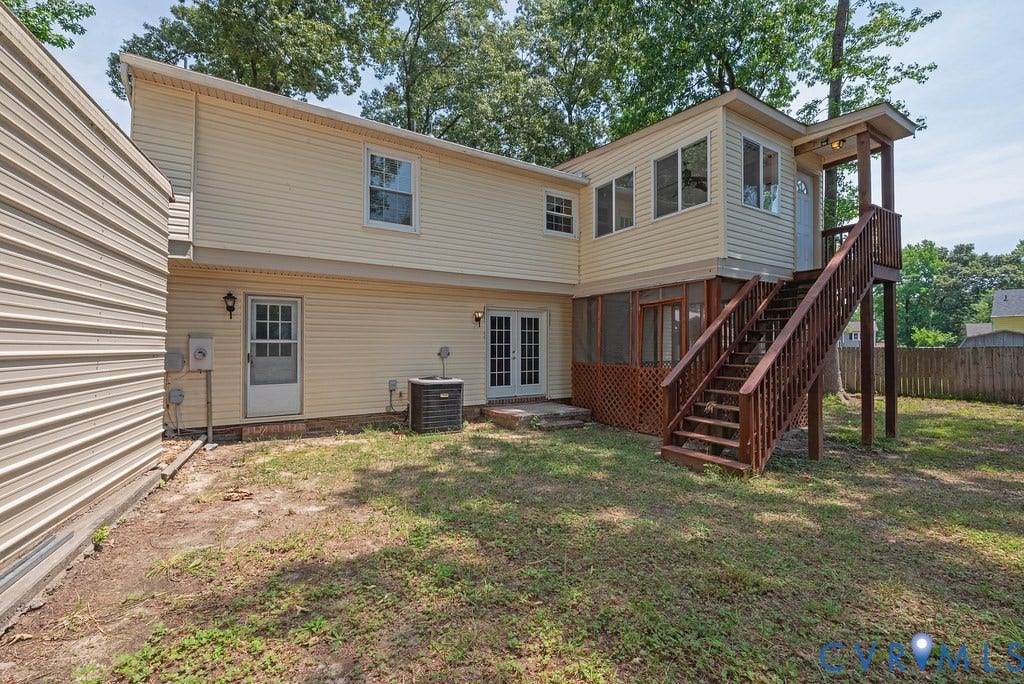 Expansive backyard featuring a two-story residence with a screened porch, an upper-level sunroom, and a multi-level wooden deck with stairs