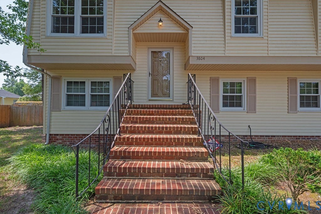 Brick entry steps with wrought iron railings leading to the main entrance