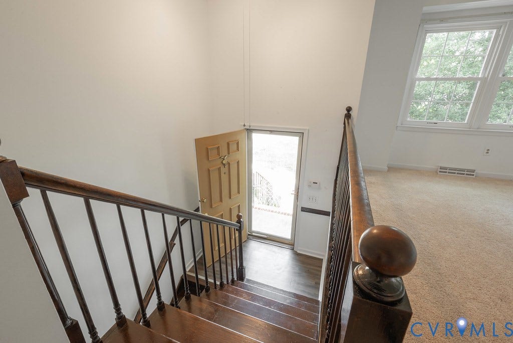 Entryway featuring wood-finish stairs with a dark wood banister and balusters
