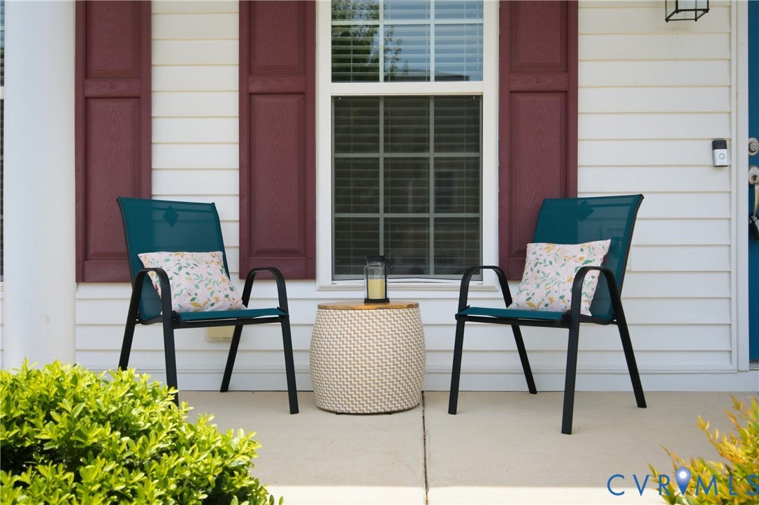 Front porch featuring white horizontal siding, red window shutters, a white framed window with internal blinds, and concrete flooring