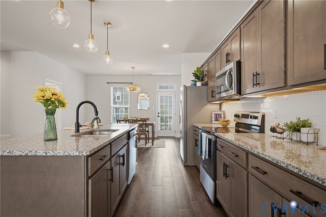 Modern kitchen featuring wood-finish flooring, granite countertops, and stainless steel appliances