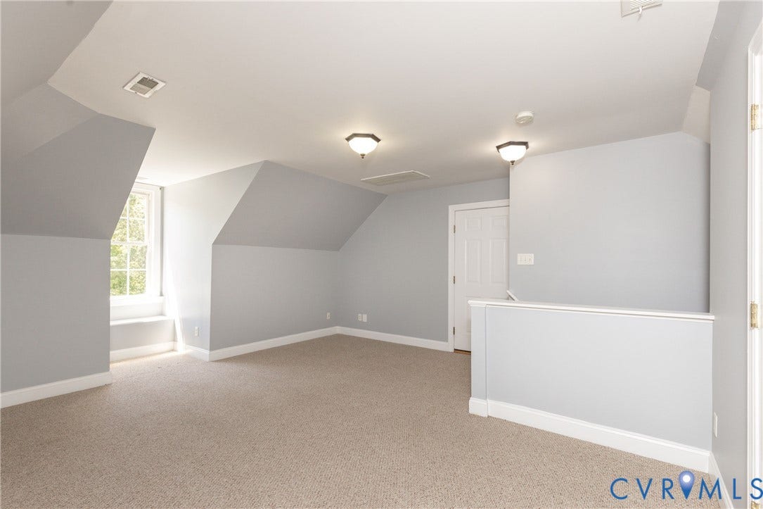 Carpeted room with sloped ceilings, a single window, and white trim