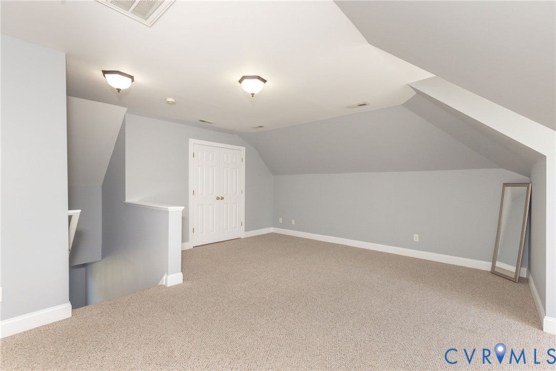 Carpeted room featuring a neutral color palette, sloped ceilings, and a built-in closet with bifold doors