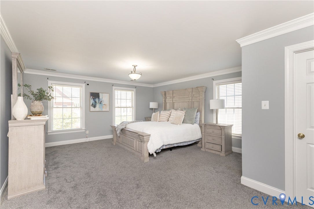 Spacious room featuring light gray walls, plush gray carpeting, white trim, and crown molding