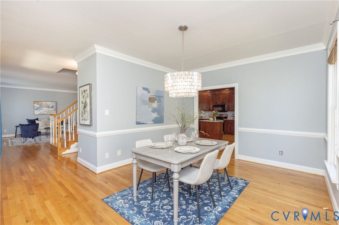 Dining area featuring hardwood flooring, a contemporary chandelier, and wainscoting
