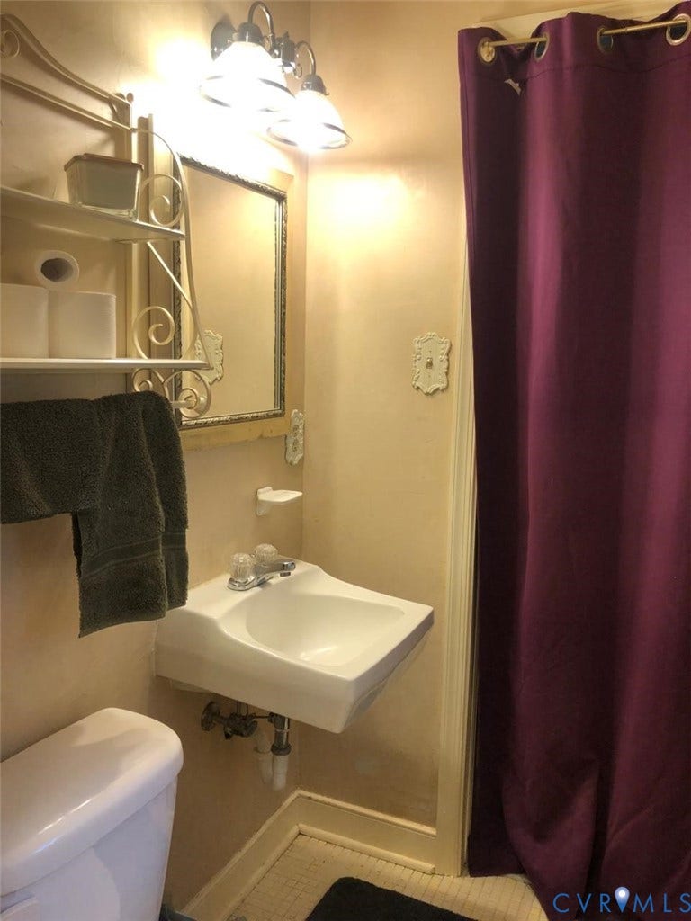 10001 Alfaree Road, Kendale Acres Addition, Chester, VA 23237 Wall-mounted vanity sink with chrome faucet, a wall-mounted mirror with decorative frame, and a three-light vanity fixture