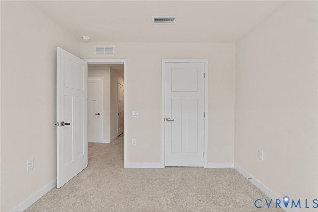 7213 Lyon Taylor Lane, Summer Maple, New Kent, VA 23124 Neutral-toned room featuring light-colored carpeting, white baseboards, and two paneled interior doors with brushed nickel hardware