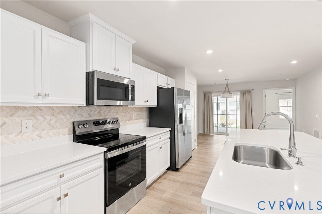 7213 Lyon Taylor Lane, Summer Maple, New Kent, VA 23124 Kitchen featuring white shaker-style cabinetry, stainless steel appliances, white countertops, a herringbone tile backsplash, and wood-finish flooring