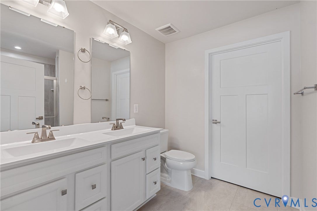 7213 Lyon Taylor Lane, Summer Maple, New Kent, VA 23124 Bathroom featuring a double vanity with integrated sinks, brushed nickel fixtures, two large mirrors, and a panel door