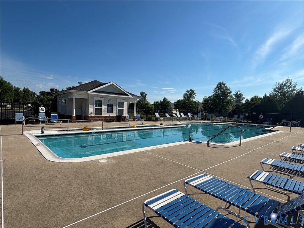 7213 Lyon Taylor Lane, Summer Maple, New Kent, VA 23124 Outdoor swimming pool with concrete decking, perimeter metal fencing, and a white siding pool house featuring a dark shingle roof