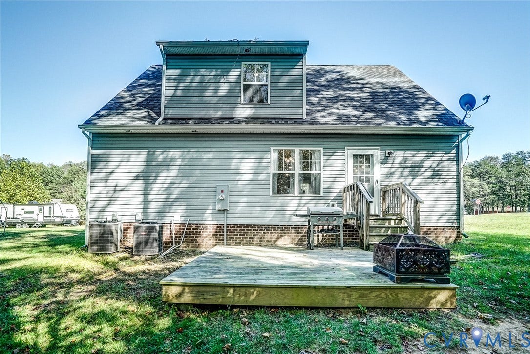 65 Hopeful Church Lane, Bumpass, VA 23024 Rear exterior featuring a wood deck, light gray siding, a dormer window, an exterior door with stairs, and a surrounding grassy area