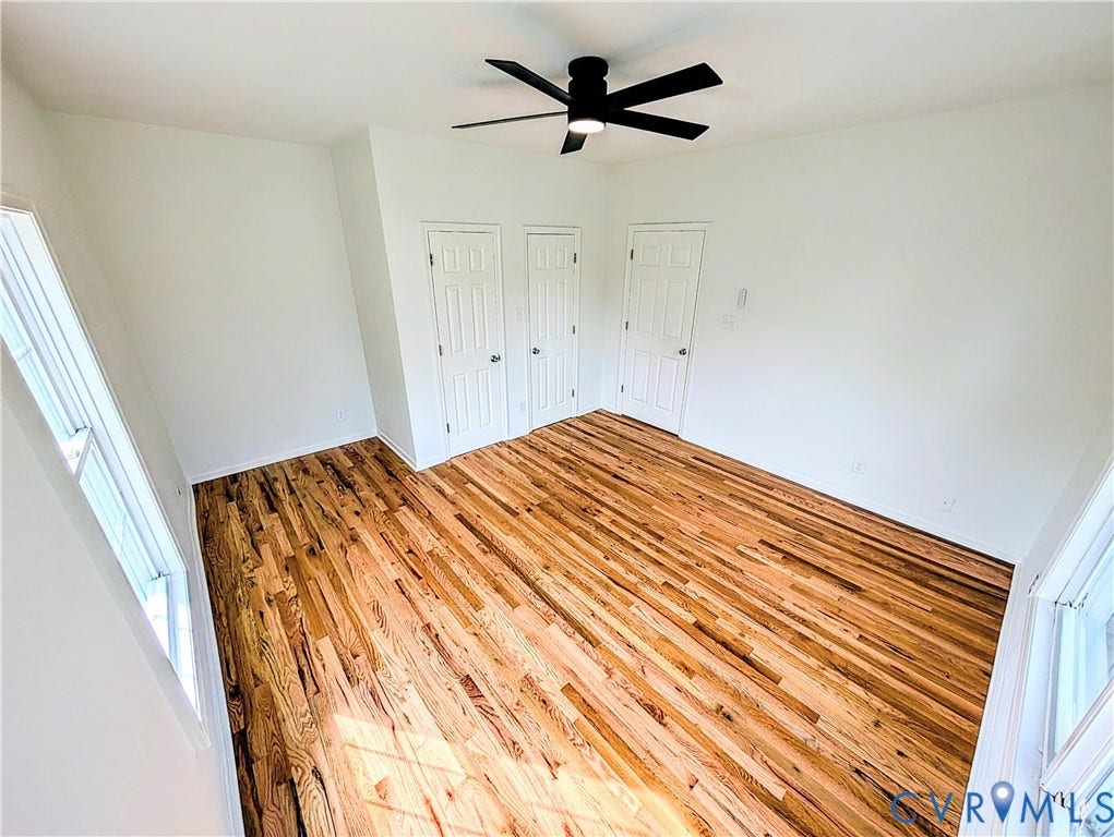 3216 Enslow Avenue, Richmond, VA 23222 Spacious room featuring rich wood-finish flooring, a modern black ceiling fan, and multiple white paneled doors