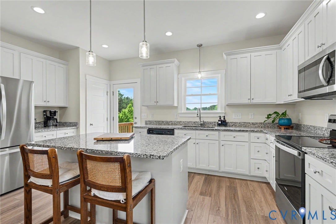 815 Kennon Road, Northeast Creek Reservoir Subd, Mineral, VA 23117 Bright kitchen featuring a central island, white cabinetry, speckled countertops, stainless steel appliances, and wood-finish flooring