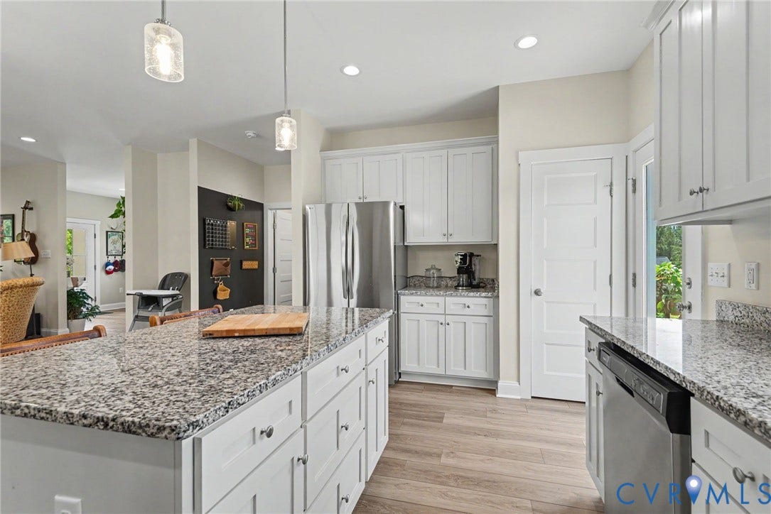 815 Kennon Road, Northeast Creek Reservoir Subd, Mineral, VA 23117 Kitchen featuring an expansive island with a light-colored speckled countertop, white cabinetry with silver hardware, stainless steel appliances, and wood-finish flooring