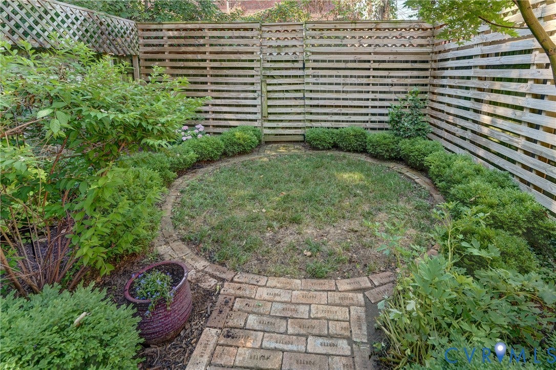 2619 Grayland Avenue, Byrd Park/Upper Fan, Richmond, VA 23220 Enclosed backyard featuring a circular lawn area, framed by a brick border and lush shrubs