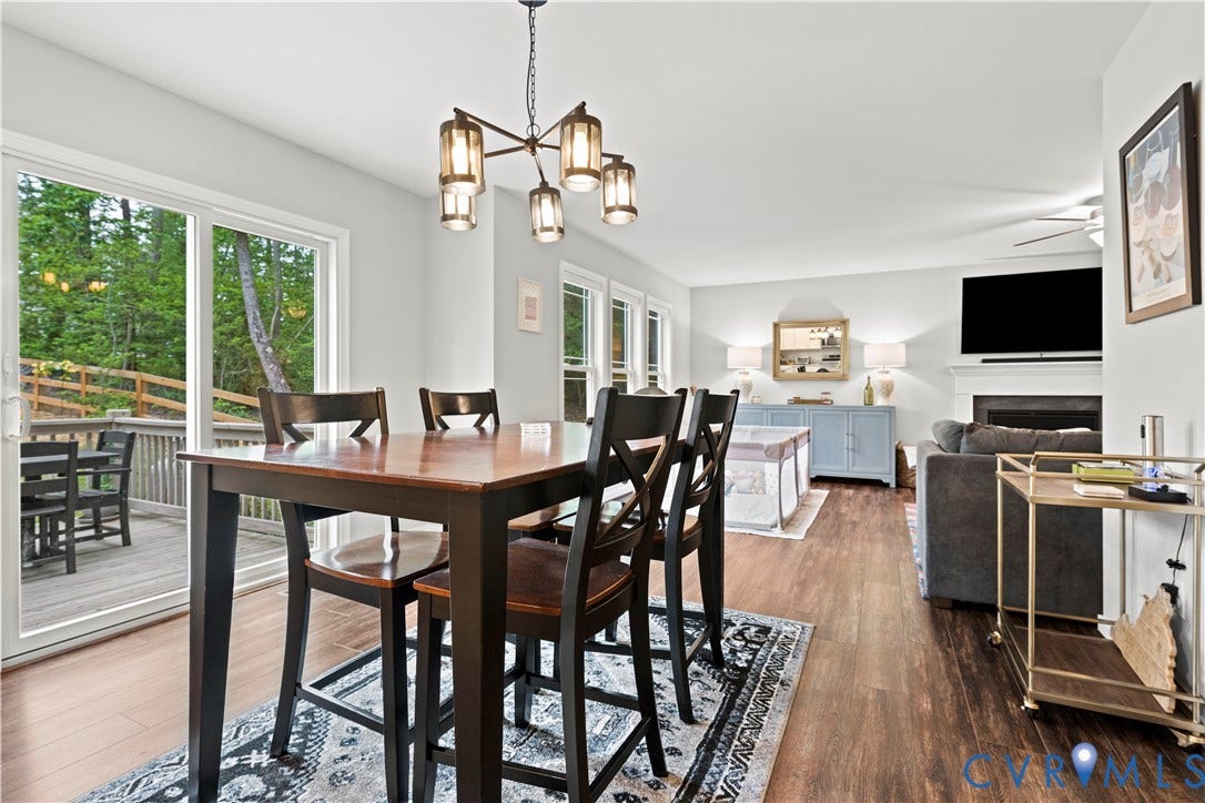 Open-concept living area featuring wood-finish flooring, a contemporary chandelier, and a white fireplace mantel