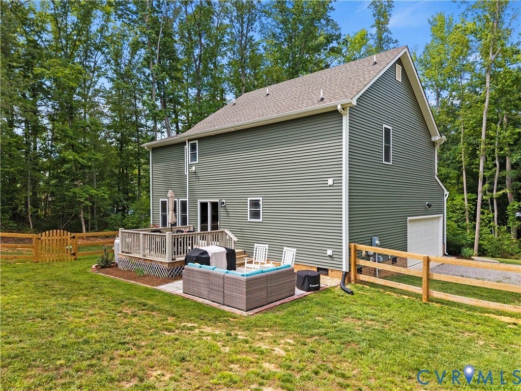 Rear exterior featuring green horizontal siding and a composition shingle roof