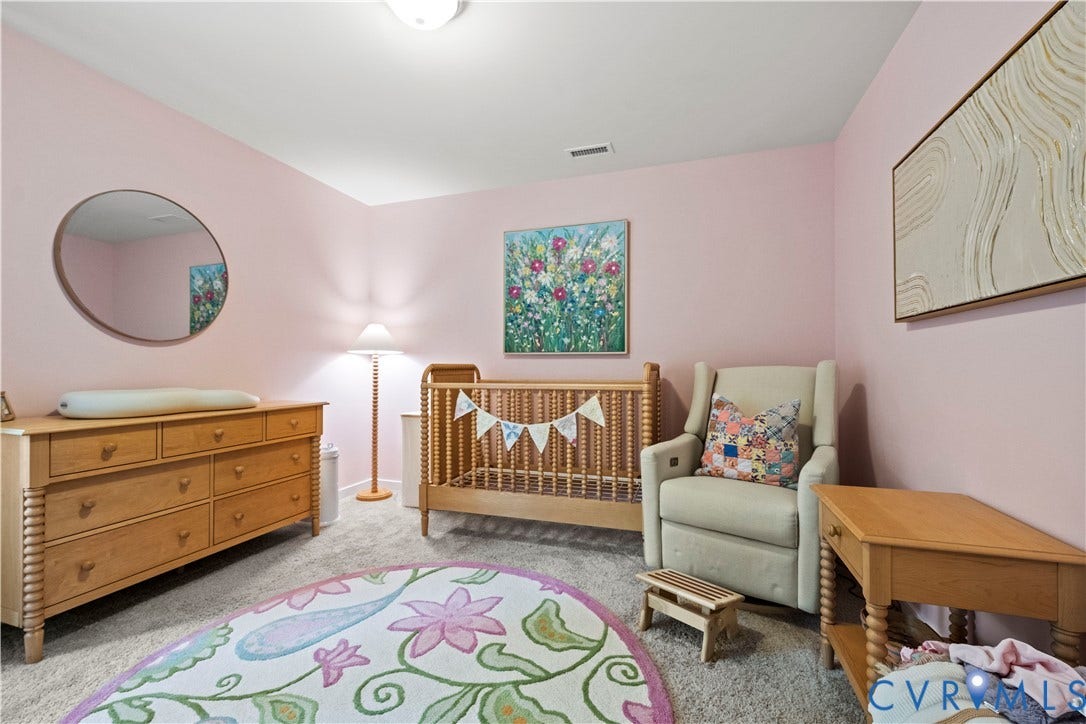 Carpeted room featuring a ceiling-mounted light fixture and a wall-mounted mirror with a wood frame