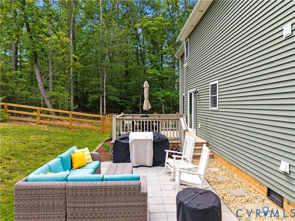 Expansive outdoor living area featuring a paver patio and a wooden deck