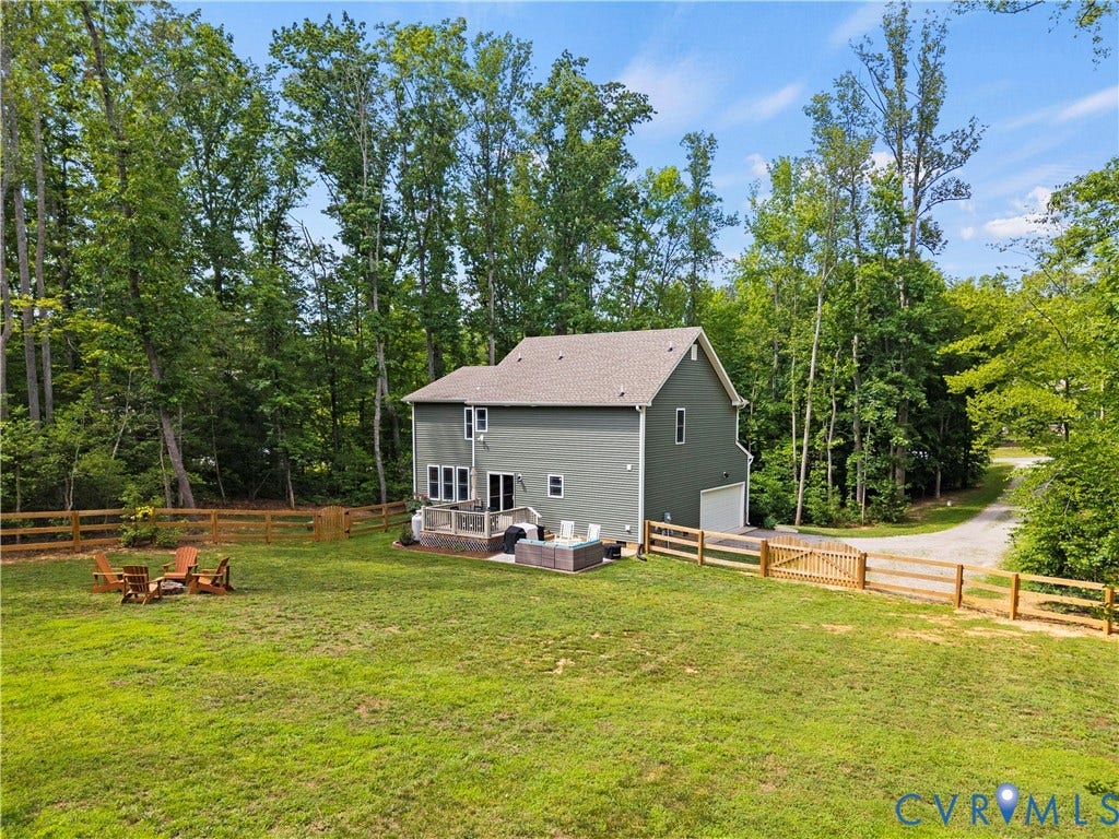 Green siding property featuring a spacious backyard, a multi-level patio, and a gravel driveway