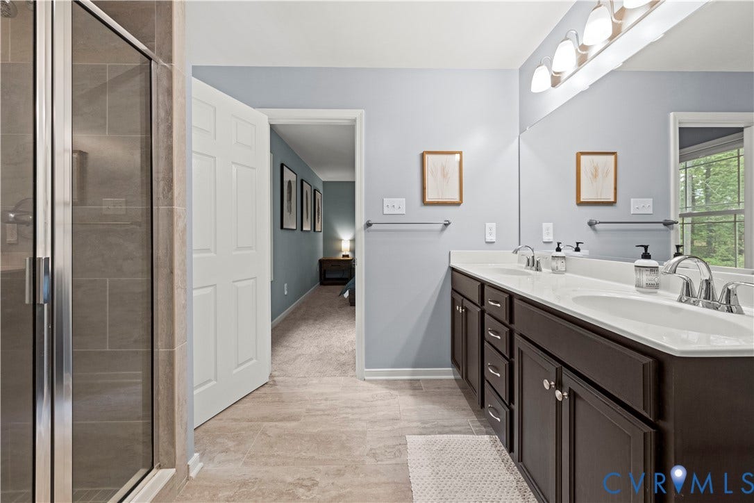 Double vanity with white countertops, dark wood cabinetry, and chrome fixtures