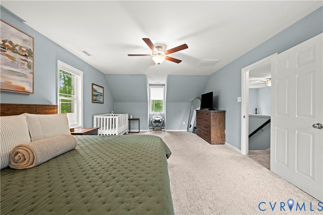 Spacious bedroom featuring light blue walls, two windows, recessed ceiling, and a ceiling fan with integrated lighting