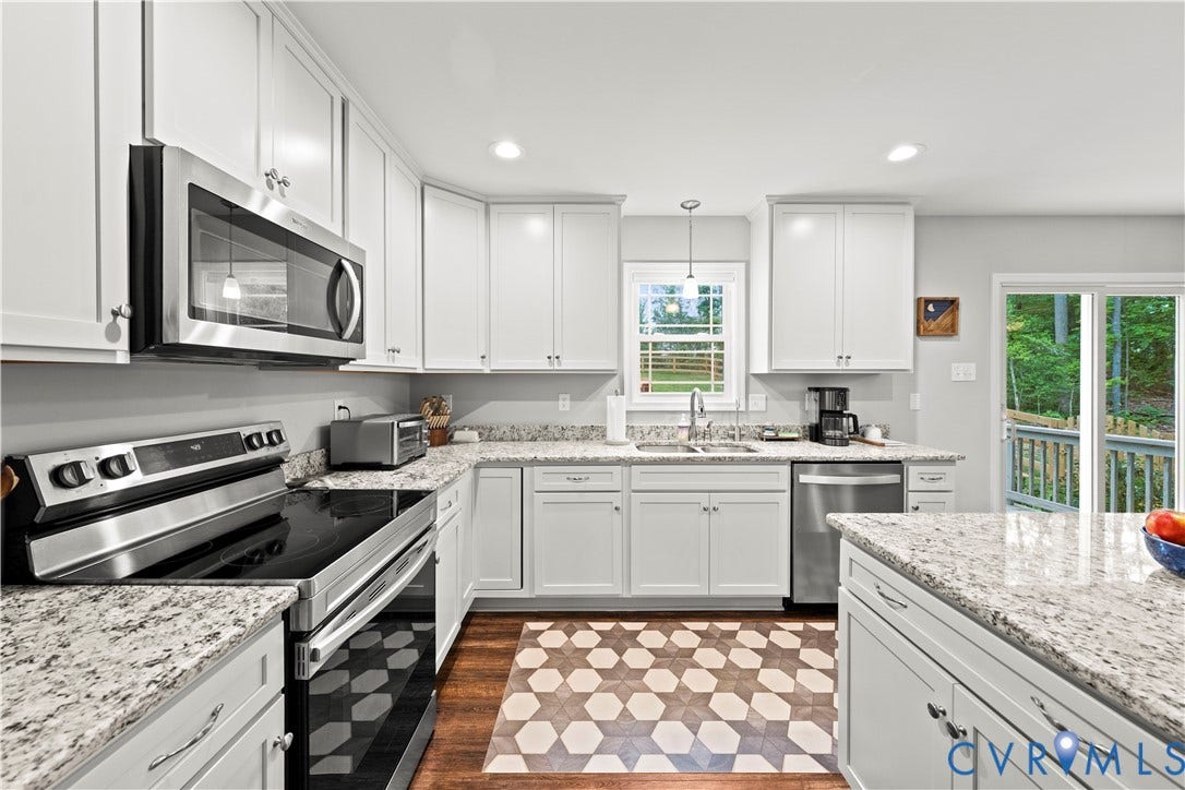 Kitchen featuring white cabinetry, light-toned countertops, and stainless steel appliances, including an oven/range, microwave, and dishwasher