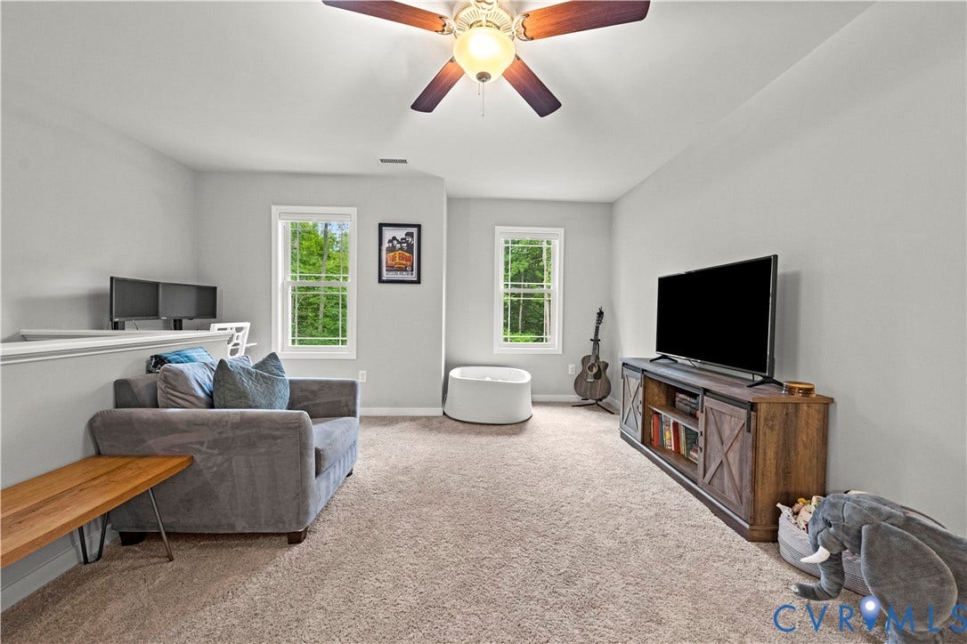 Carpeted room with light gray walls, white trim windows, and a ceiling fan