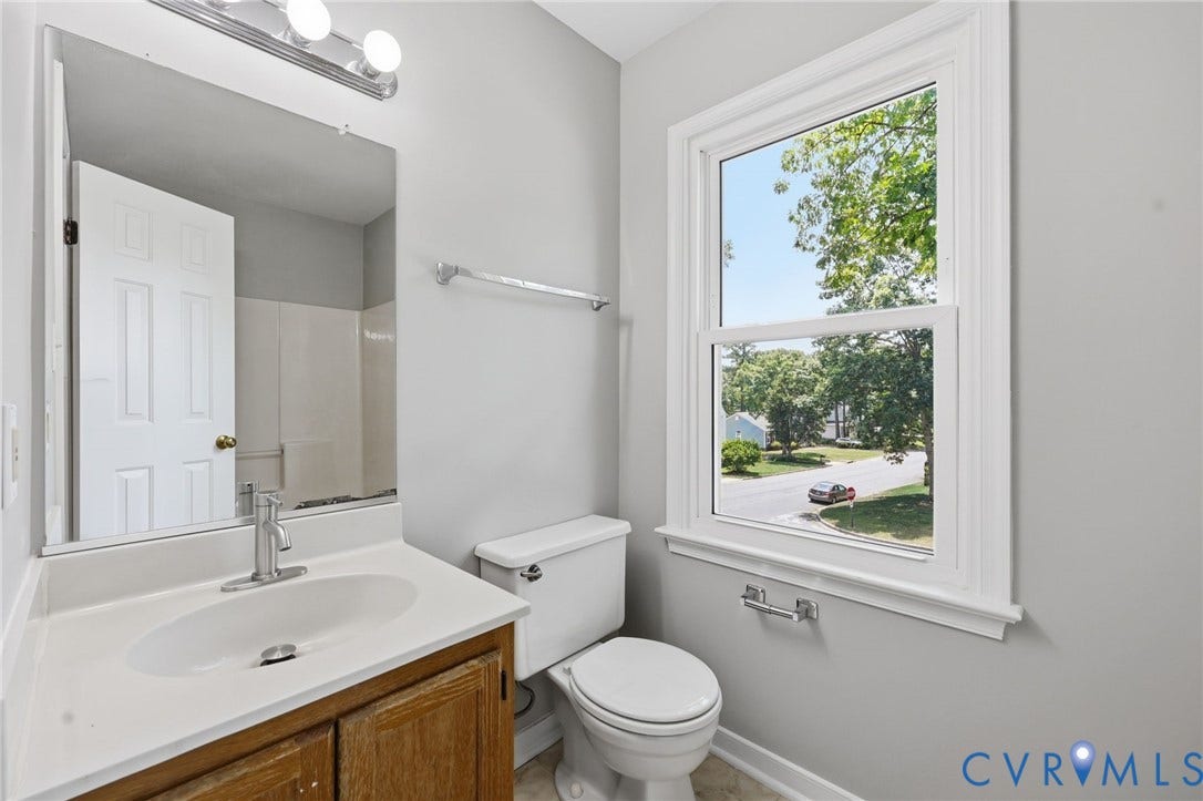 9500 Mesquite Road, Glen Allen, VA 23060 Bathroom featuring a single vanity with wood-finish cabinetry and an integrated sink, a white toilet, and a window with white trim